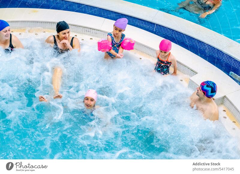 Family relaxing in bubbling pool family swimming bubbles parents daughters talking together amusement park water fun leisure rest girls kids children siblings