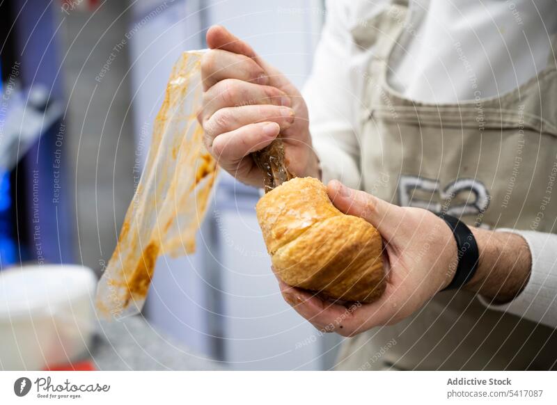 Confectioner pouring chocolate filling into croissant fresh bakery dessert food pastry french traditional dough patisserie hot tasty brown delicious gourmet