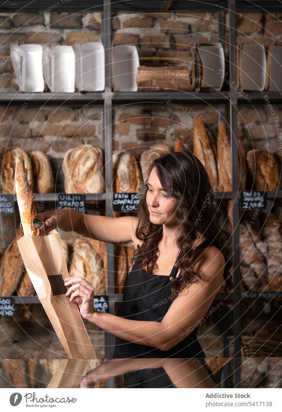 Young female selling baguettes woman bakery bread french traditional fresh food occupation job young person beautiful attractive pretty brunette standing