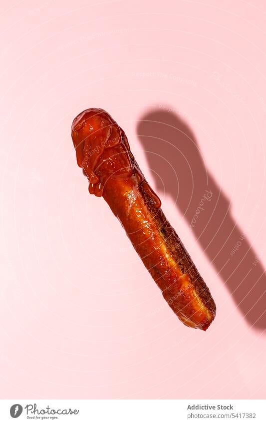 delicious grilled sausage full of ketchup in a pink background clipping path meal gastronomy unhealthy close-up roasted meat prepared ingredient fried