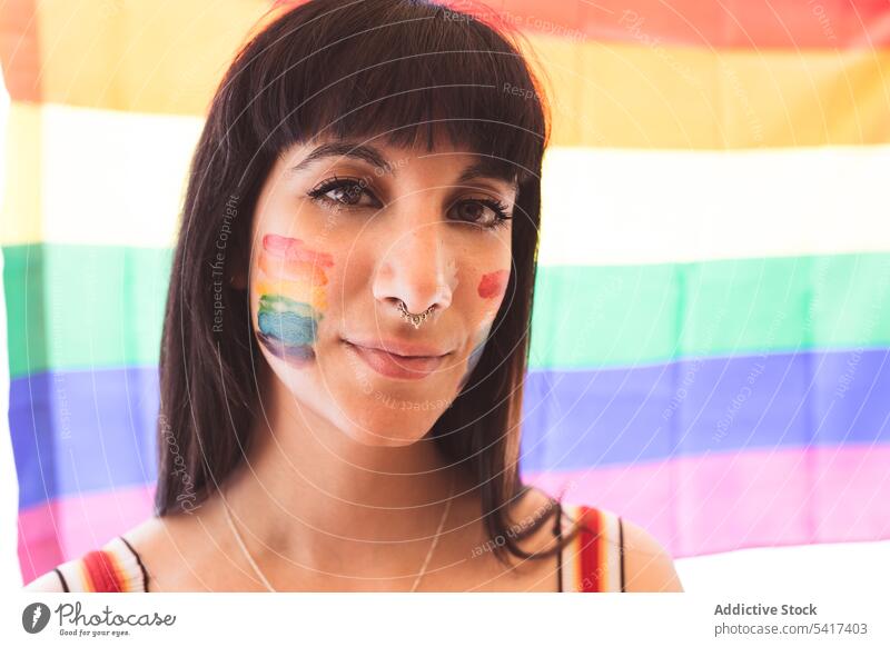 Brunette woman with LGBT symbol on face straightening hair beautiful lgbt attractive young pretty sensual freedom equality rights cheerful female tolerance