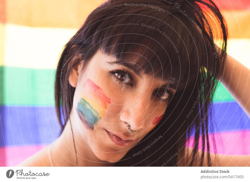 Brunette woman with LGBT symbol on face straightening hair beautiful lgbt attractive young pretty sensual serious freedom equality rights cheerful female