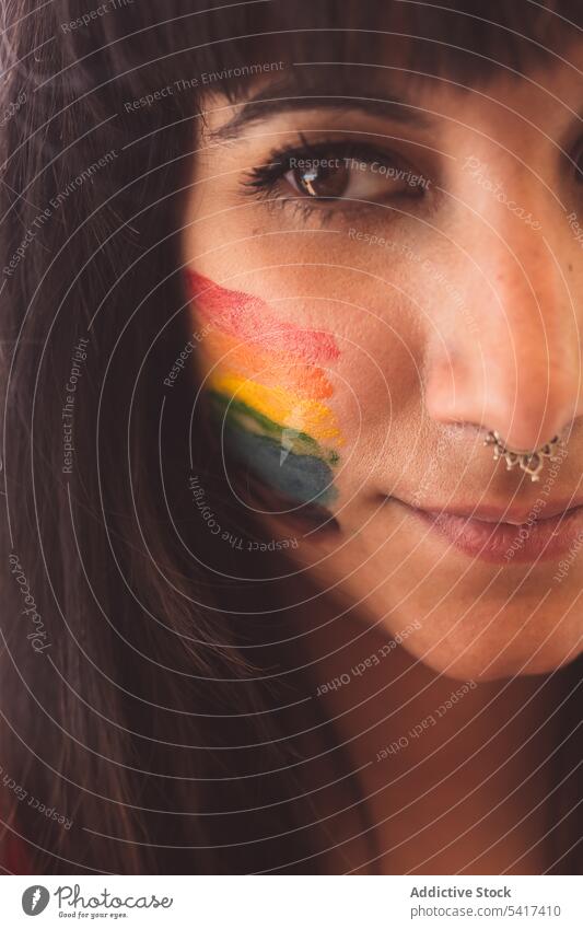 Brunette woman with LGBT symbol on face straightening hair beautiful lgbt attractive young pretty sensual serious freedom equality rights female tolerance