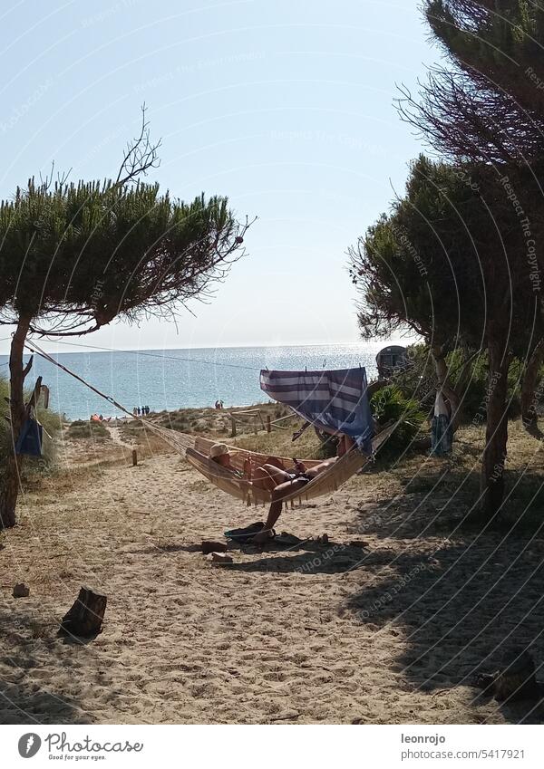 A couple is comfortably lying in a hammock enjoying the day at the sea and beach of Tarifa. Beach coast Sand Ocean Water Vacation & Travel Exterior shot