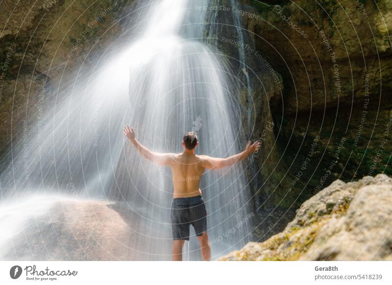 young adult man in a waterfall in the jungle of thailand adventure back view background beauty body cascade climate environment flowing freedom fresh hands