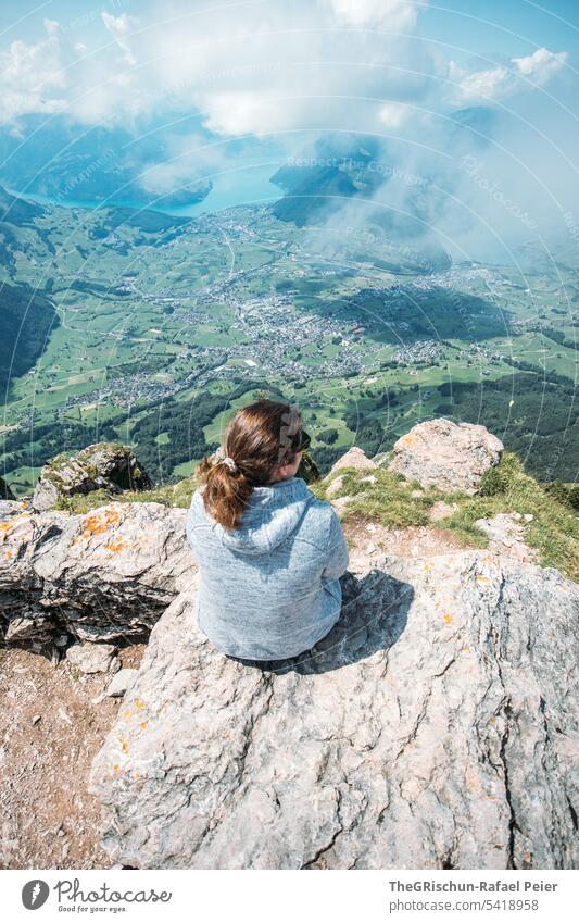 Woman sitting on stone and looking into the distance Colour photo big myths Mountain Hiking Switzerland Tourism Alps Landscape Exterior shot Hiking poles Rock
