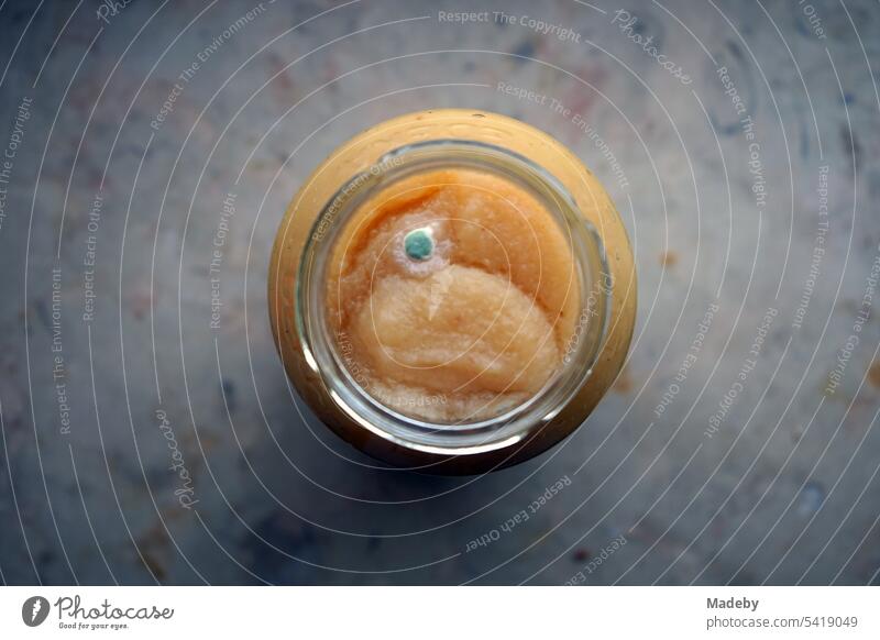 Boiled down applesauce in an open canning jar with mold or mildew on the windowsill in the pantry in Oerlinghausen near Bielefeld in the Teutoburg Forest in East Westphalia-Lippe