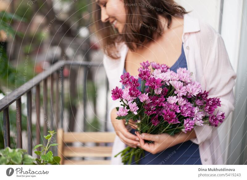 Beautiful woman with flowers bouquet on the balcony closeup. Happy brunette smiling. Plants and flowers gardening hobby. Balcony plant Balcony furnishings
