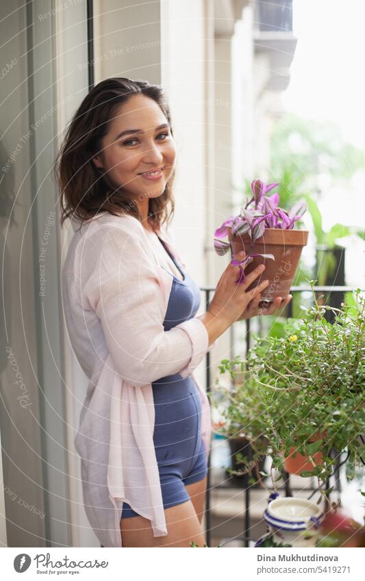 Beautiful woman with houseplant on the balcony. Happy brunette smiling. Plants and flowers gardening hobby. Balcony plant Balcony furnishings Summer Pot plant
