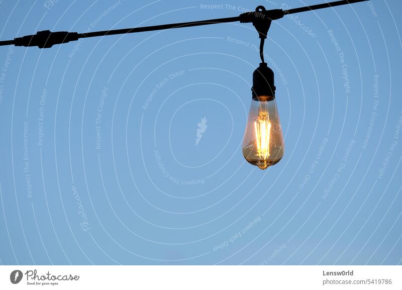 Single light bulb against a clear sky background blue bright concept copy space creativity electric electricity energy glass hanging idea idea concept