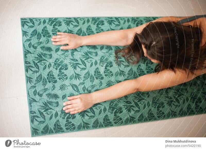 Arms stretching on yoga mat. Young woman practicing yoga on green mat at home. Doing sport, wellness and healthcare. Indoor yoga online class. Mindfullnesss and meditation, active lifestyle.