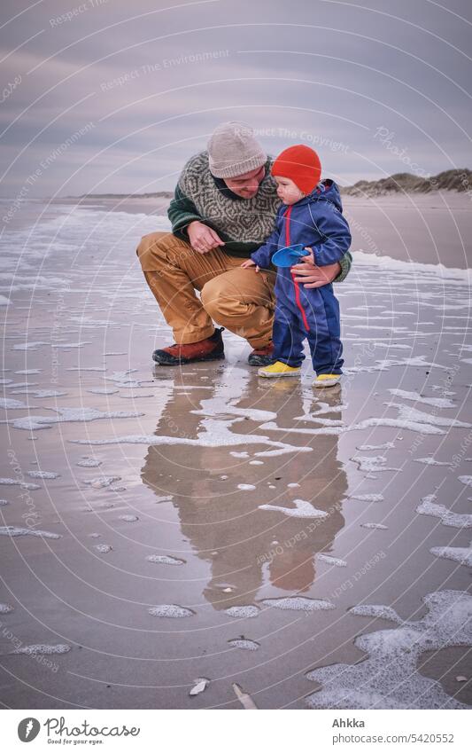 Man with toddler dressed warmly on deserted beach Father Toddler Beach Ocean Affection Water Waves coast Together Accompany Outdoors naturally vacation