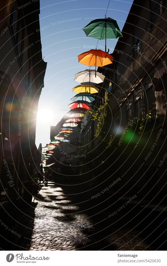 schattenwerfende Regenschirme in der Gelnhäuser Langgasse im Gegenlicht am Abend Schirm farbenfroh Schatten Sonnenstrahlen Gelnhausen Regenbogenfarben