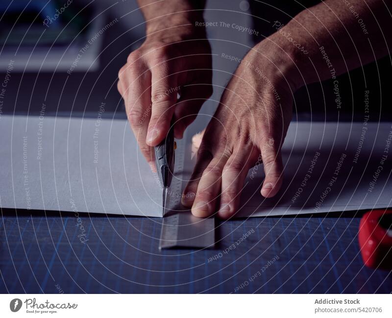 Worker cutting sheet with stationery knife on surface artisan bookmaking page typography craft binding workplace production sharp manual assembling decor