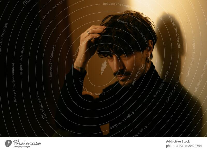 Stylish guy sitting near wall with hand in hair and resting man think lonely problem brunet cool solitude handsome mustache ring male earring shadow bristle