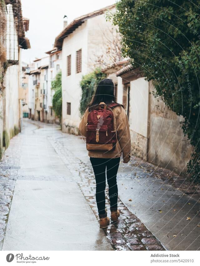 Female traveler walking in old town woman backpack street city architecture building active style vacation destination young urban sightseeing explore narrow