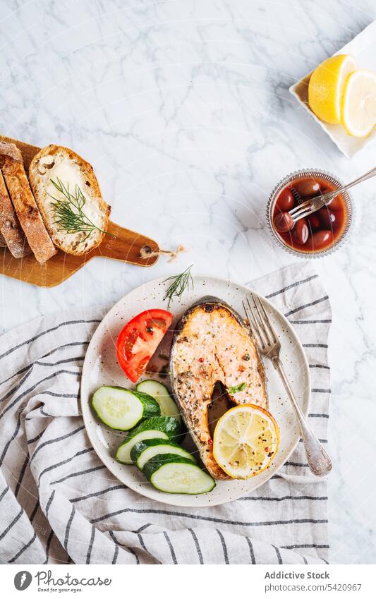 Healthy dish with fish and vegetables steak salmon salad healthy plate serve dinner grill food cucumber tomato lemon herb aromatic bread olive mediterranean