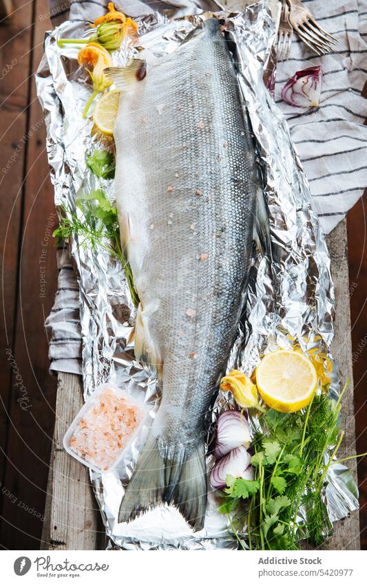 Fresh salmon fish with seasoning on aluminum foil fresh lemon herb raw prepare ingredient whole seafood healthy tasty natural meal cilantro parsley citrus dish
