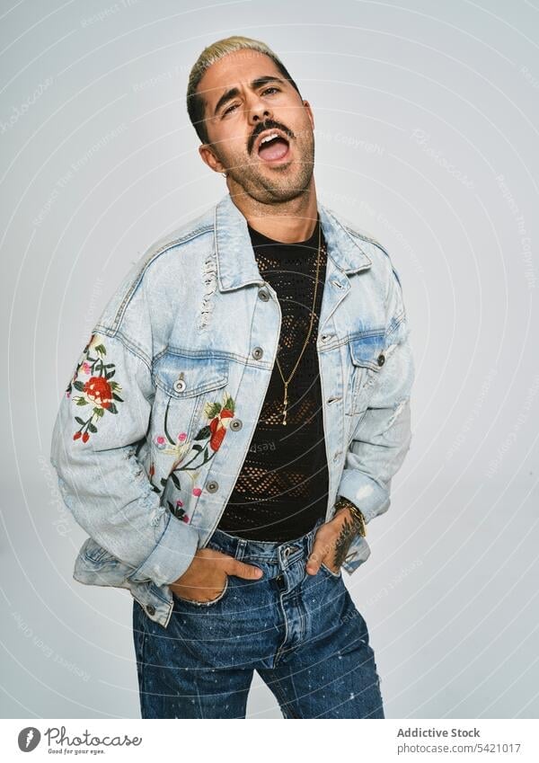 Stylish grimacing man in denim outfit trendy independent cool expressive grimace naughty style modern hipster provocative young ethnic male jacket mustache