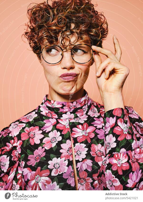 Doubtful woman in trendy outfit fashion style doubt thoughtful eyeglasses colorful floral young female model pensive accessory eyewear curly hair vintage