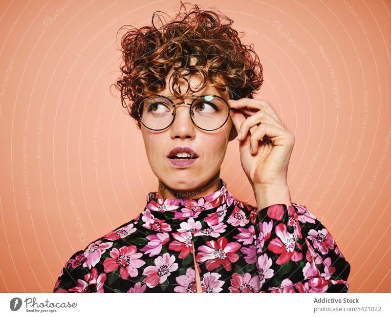 Doubtful woman in trendy outfit fashion style doubt thoughtful eyeglasses colorful floral young female model pensive cloth accessory eyewear curly hair vintage