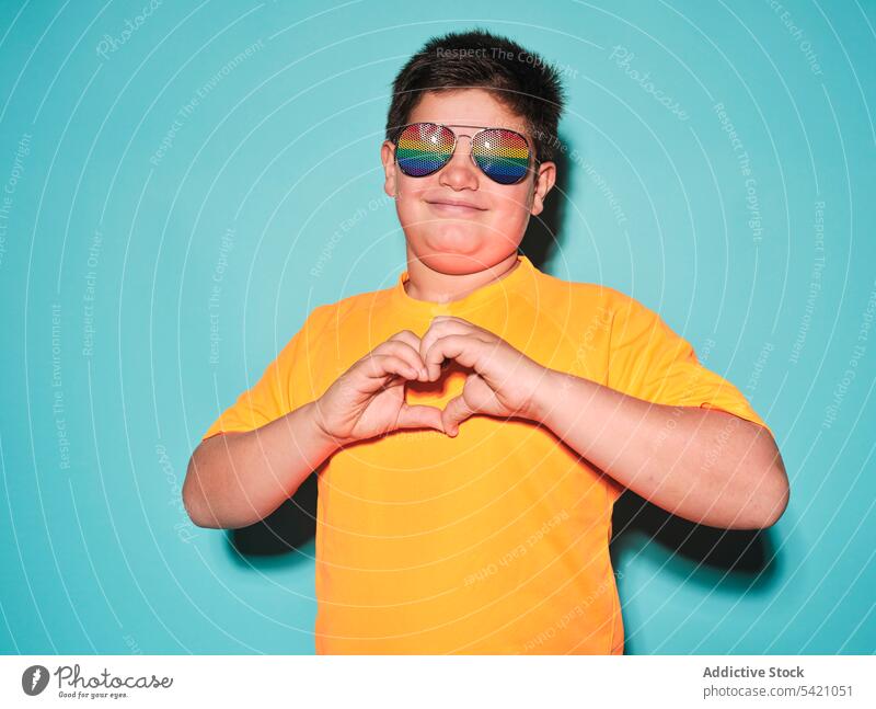 Happy boy showing heart sign with hands kid gesture style sunglasses smile positive plump casual bright yellow color male child preteen cheerful happy trendy