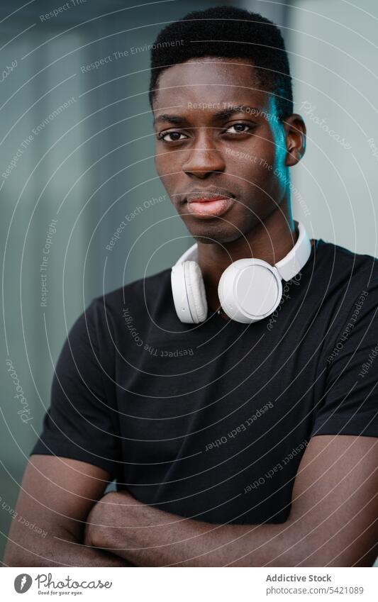 Black man with headphones on street frown modern urban casual ethnic city male gadget device serious black african american displease problem sit unhappy town