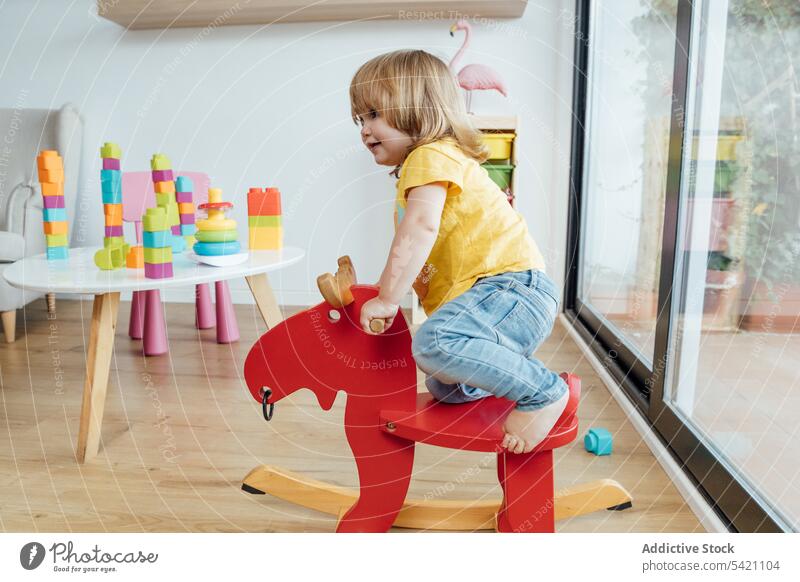 Happy kid riding toy horse in nursery play ride happy fun joy colorful infant little child baby education childhood adorable cute game playful smile enjoy
