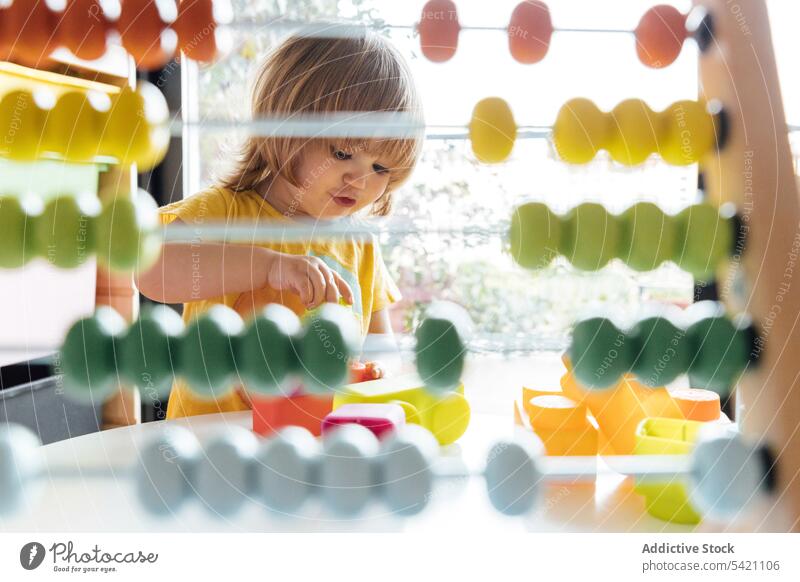 Cute little kid playing with colorful abacus counter score toy education learn develop child childhood adorable game preschool concentrate small infant activity