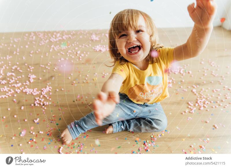 Cheerful kid having fun with colorful sprinkles play happy confetti messy preschool cheerful joy little small bead floor child childhood adorable playful cute