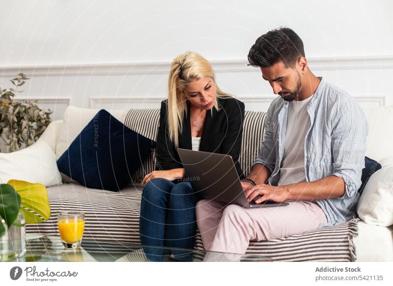Diverse couple using laptop together home sofa diverse living room man woman focus computer love couch watch girlfriend boyfriend relationship multiracial