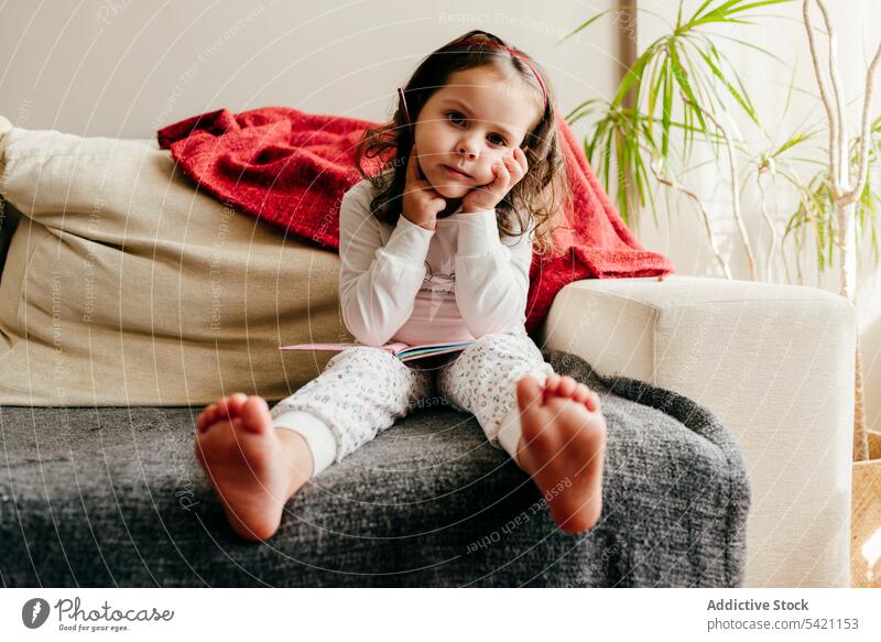 Cute little girl sitting on the couch looking for inspiration cute posing home indoors window kid child portrait childhood colorful beauty children daughter