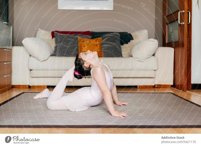Flexible little gymnast training at home girl flexible floor living room exercise cozy gymnastic stretch child kid bend touch head feet carpet sofa couch
