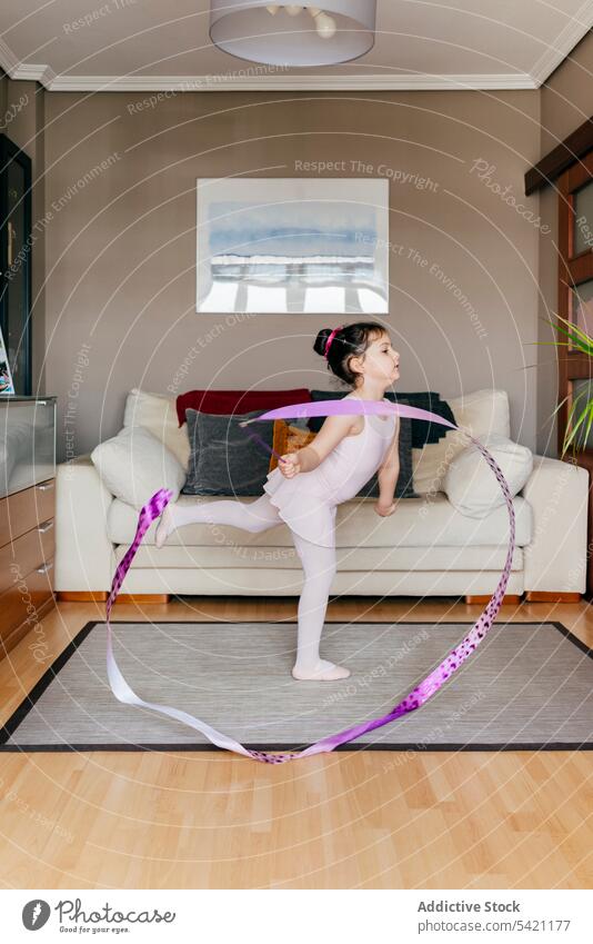 Little gymnast exercising with ribbon at home girl gymnastic dance rehearsal rhythmic spin training little leotard tights living room child dancer childhood