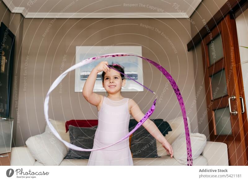 Little gymnast exercising with ribbon at home girl gymnastic dance rehearsal rhythmic spin training little leotard living room child dancer childhood perform