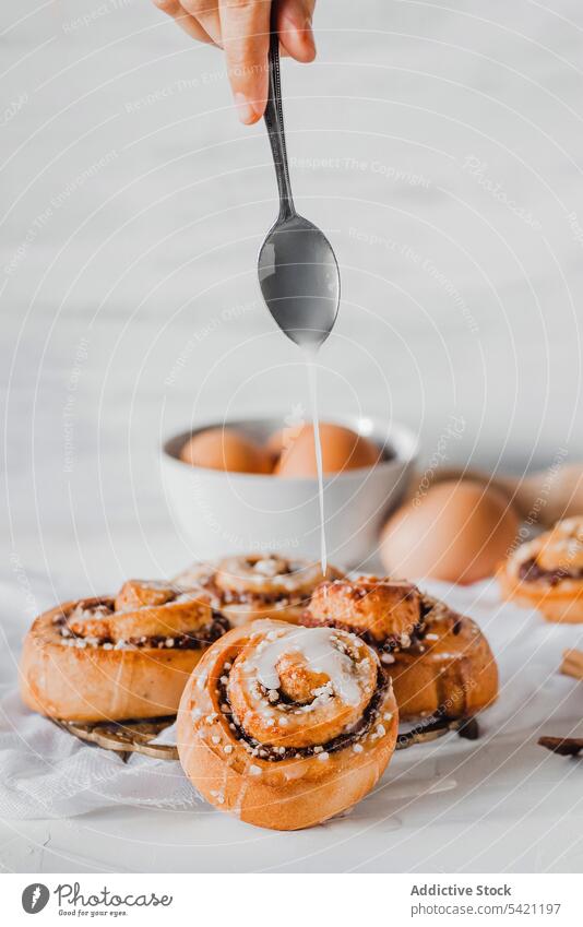 Cook pouring icing on fresh baked cinnamon rolls bun top sugar sweet bakery sprinkle food prepare natural gourmet homemade cuisine topping powder delicious cook