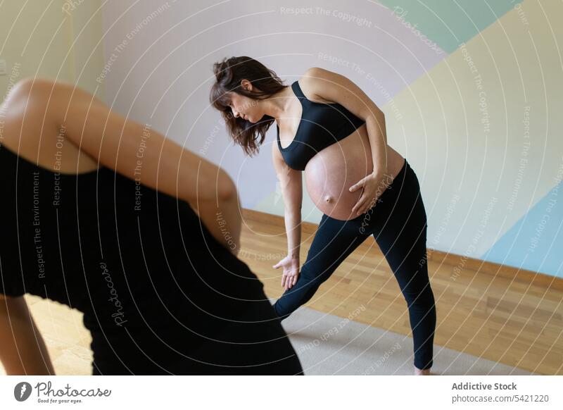 Instructor helping pregnant woman with yoga exercise women studio trainer triangle pose training together healthy wellness practice well-being belly workout