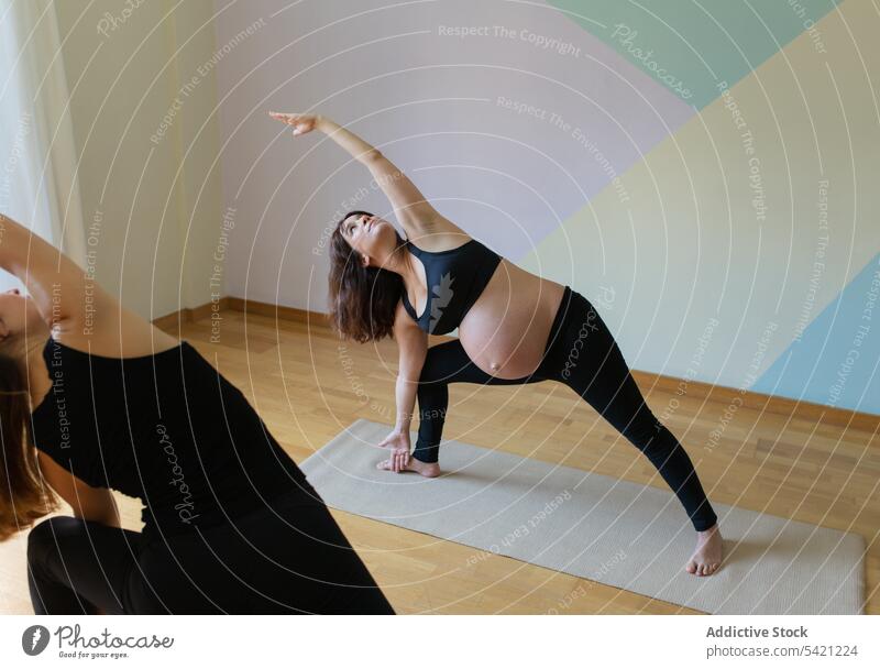 Pregnant woman doing yoga with trainer women studio extended side angle pose pregnant Utthita Parsvakonasana repeat training exercise together healthy wellness