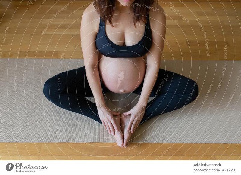 Crop pregnant woman meditating on floor yoga meditation training lotus pose belly touch balance studio sportswear female healthy wellness expect maternal tummy
