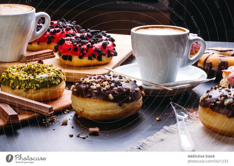 Assorted glazed doughnuts and coffee cup on slate surface sweet chocolate dessert confectionery indulge various calorie cappuccino pastry bakery sugar delicious