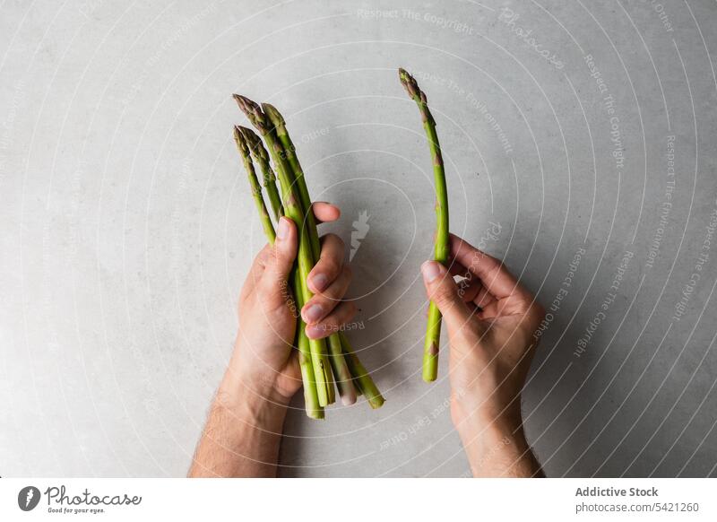 Cook holding bunch of fresh asparagus green healthy vegetarian table food hand kitchen raw cook chef plant meal diet cuisine herb prepare vegetable ingredient