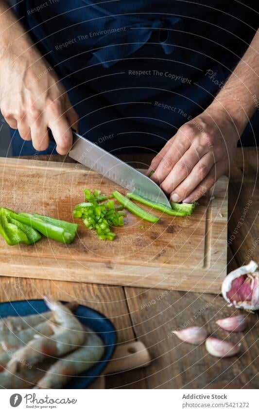 Cook cutting green chili pepper while cooking tasty savory dish in restaurant kitchen chef cutting board hand shrimp knife food garlic spicy seasoning vegetable