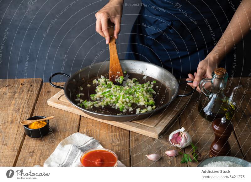 Chef mixing chopped green chili pepper and onions while cooking savory dish in restaurant kitchen pan oil spatula stir hand chef fry vegetable wooden garnish