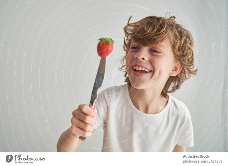 Happy boy with strawberry on knife play home happy summer smile fresh fun child kid food fruit laugh ripe carry sweet childhood cheerful organic excited playful