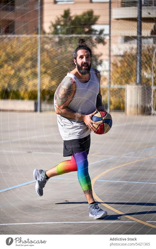 Man with a beard playing basketball on an urban court competition energy athlete street city jump training action young game player score sport outdoor activity