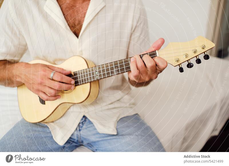 Anonymous tranquil man playing ukulele on white background music musician song serene handsome player male instrument relax peaceful harmony sound melody