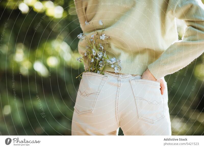 Unrecognizable teen girl with flowers in jeans pocket tender summer wildflower park teenage gentle nature stand bloom style blossom flora season carefree