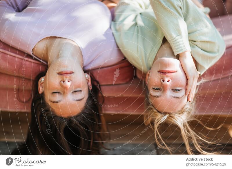 Carefree teenage sisters lying on sofa together tender serene sibling upside down carefree charming bonding relax rest couch friend friendship girl friendly