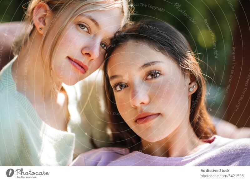 Charming teenage sisters looking at camera in park tender charming appearance together delicate girl garden nature summer sunny sunlight enjoy carefree harmony