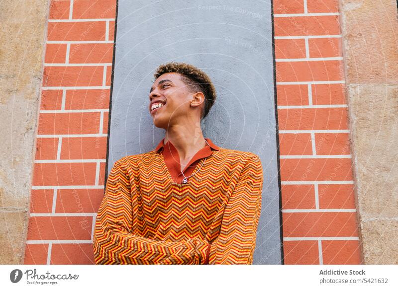 Smiling ethnic man standing on the street style color urban orange using modern young male trendy lifestyle hipster headlight colorful millennial fashion
